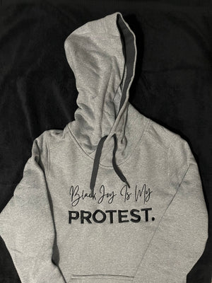 woman's fitted gray hoodie with black writing that says "black joy is my protest."