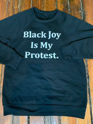 Open image in slideshow, &quot;Black Joy Is My Protest&quot; is the white text on a black sweatshirt.
